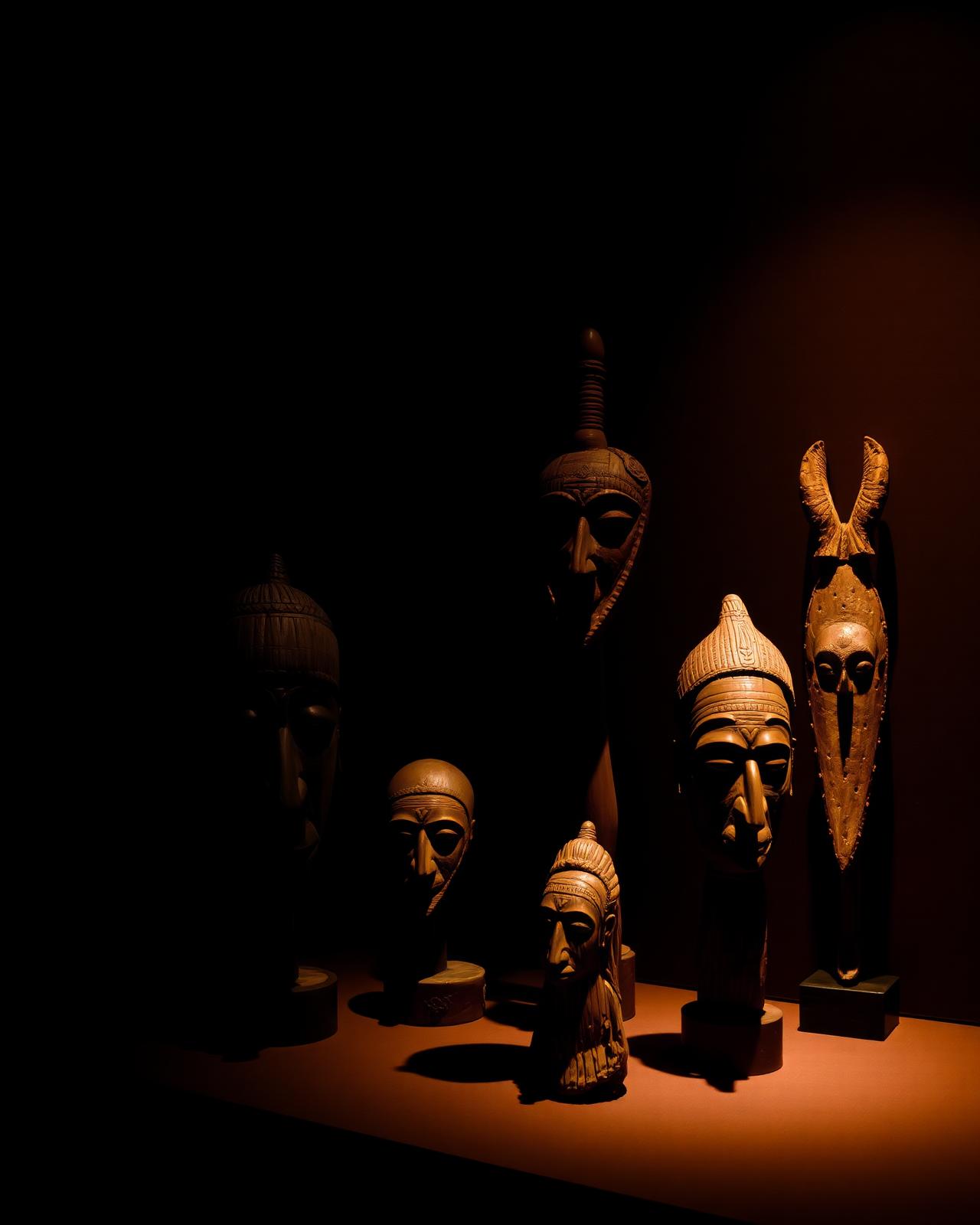 Collection de masques et sculptures africaines mis en lumière dans une galerie